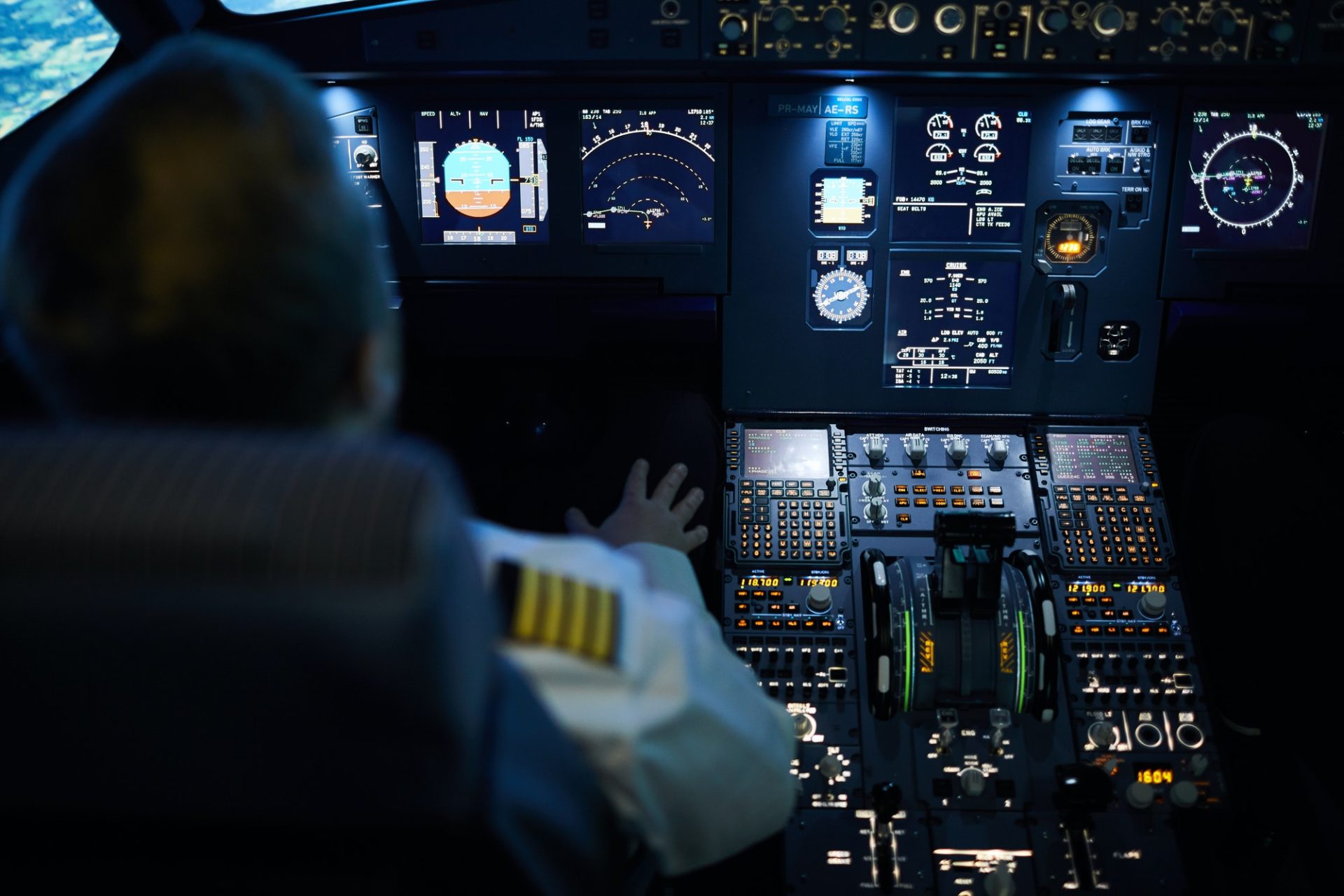 Piloto ajustando controles en la cabina de un avión durante el vuelo.
